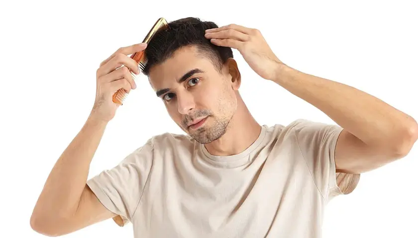 Hombre peinando su cabello, preocupado por en qué época se cae más el pelo.