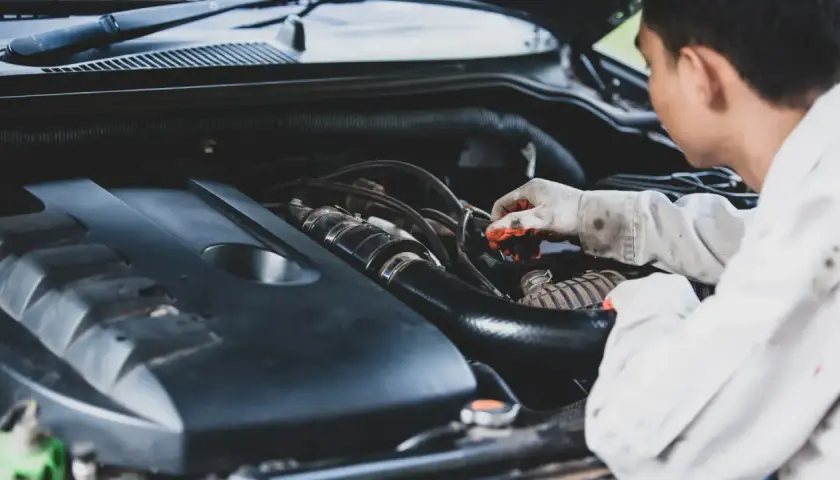 Mecánico revisa motor, buscando remedios caseros para quitar la carbonilla del coche.