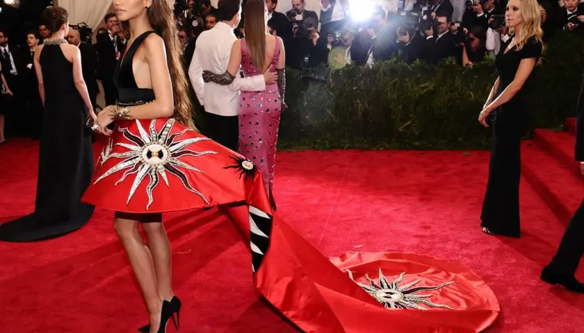 Zendaya deslumbrante en la Met Gala con un vestido rojo solar y una larga cola.