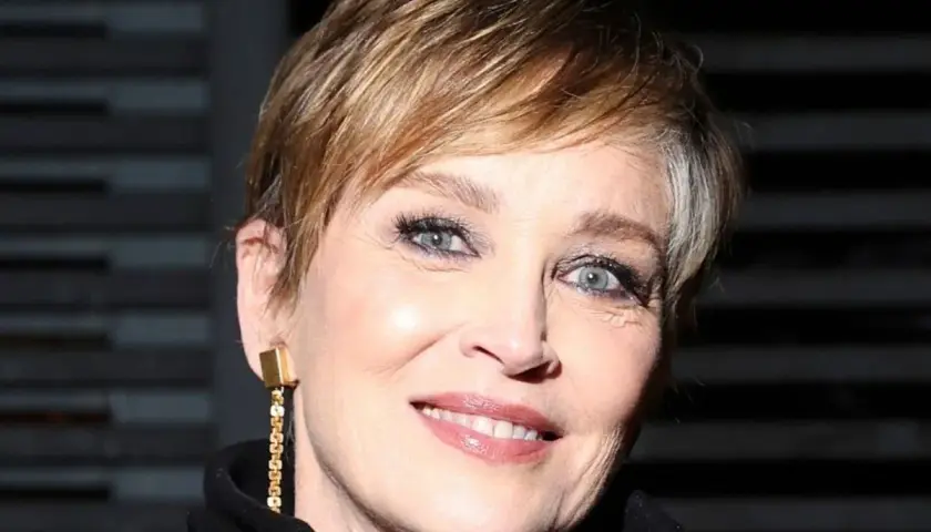 Señora sonríe con un moderno corte de cabello pixie, luciendo un elegante pendiente dorado.