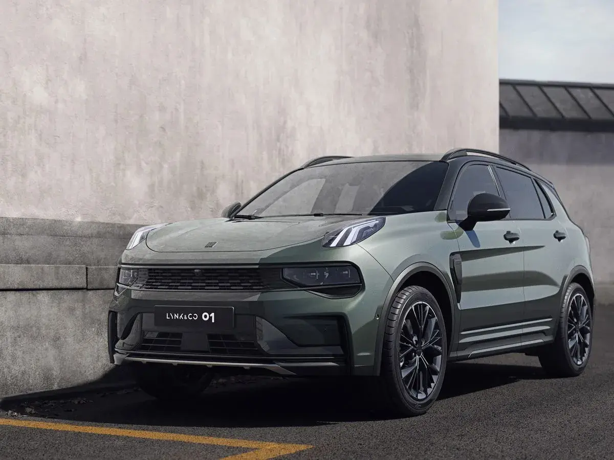 Un elegante SUV Lynk & Co 01 en color verde oscuro, aparcado junto a un muro de hormigón.