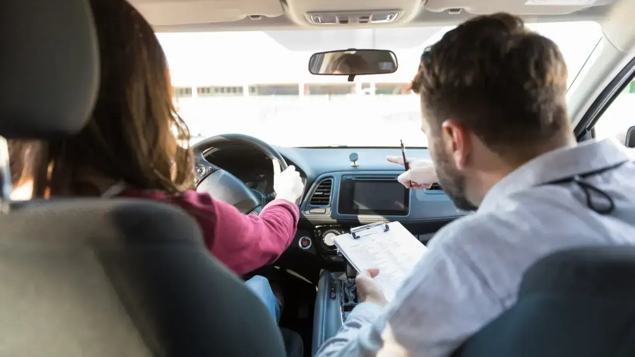 Instructor de autoescuela revisa notas mientras enseña a conducir. ¿Cuánto gana un profesor de autoescuela?