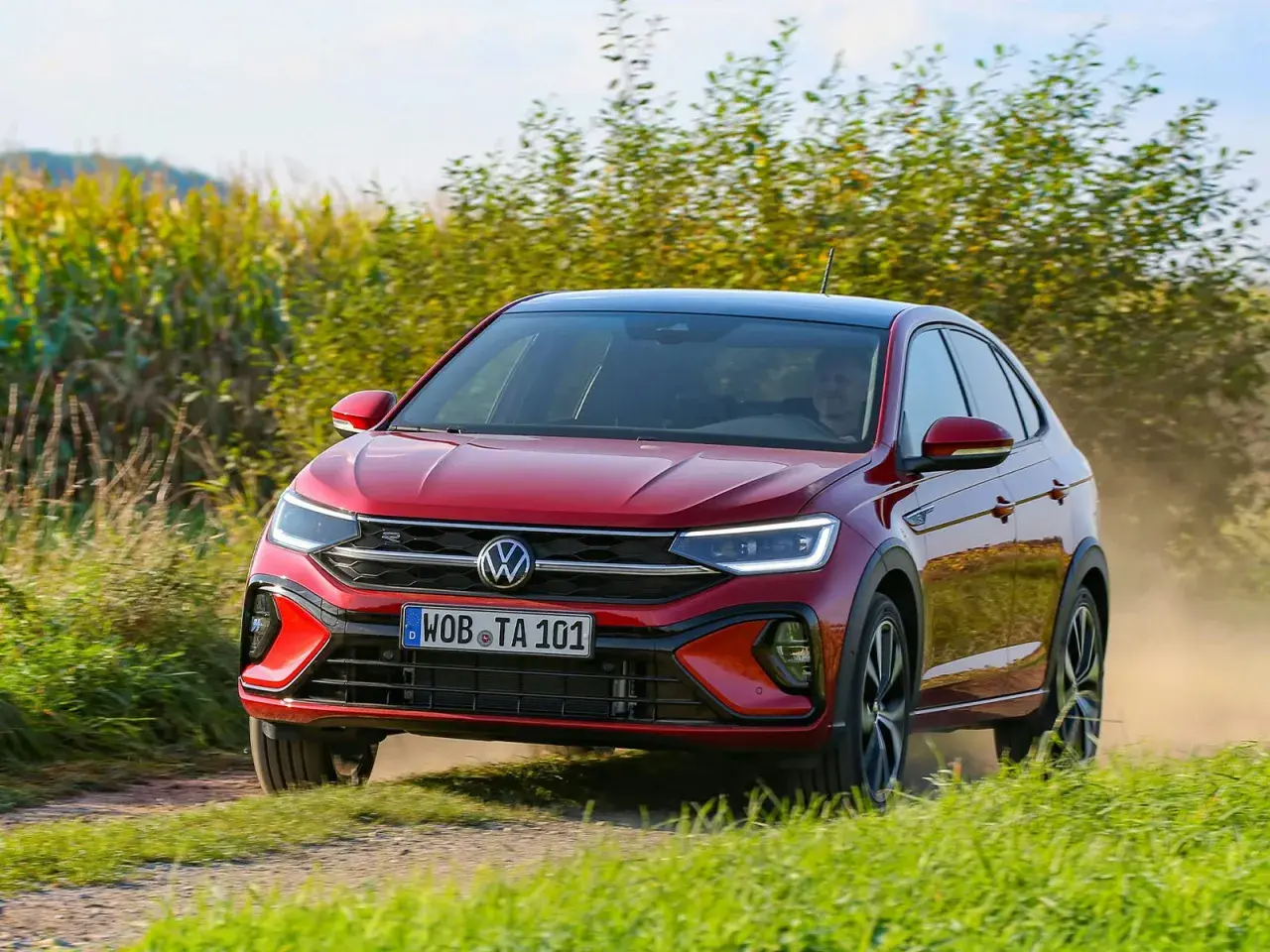 El Volkswagen Taigo rojo circula por un camino polvoriento, quizás enfrentando algunos problemas de tracción en el campo.