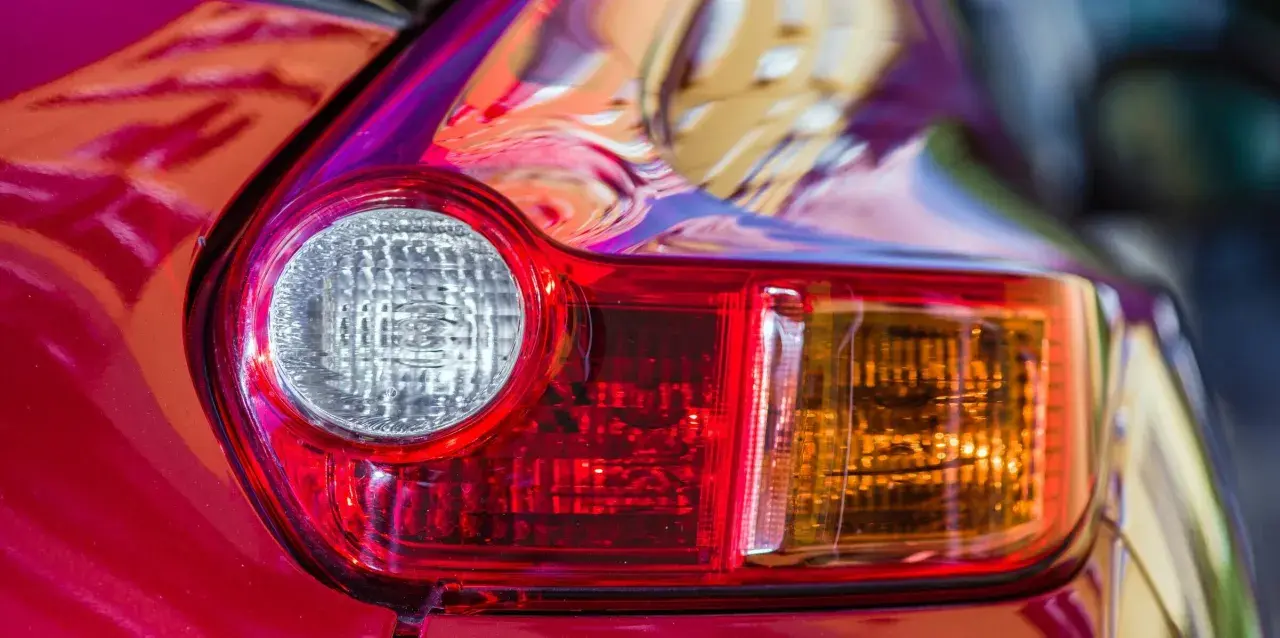 Detalle de un piloto trasero de coche rojo. Se aprecia el catadióptrico, que es un elemento reflectante de seguridad.