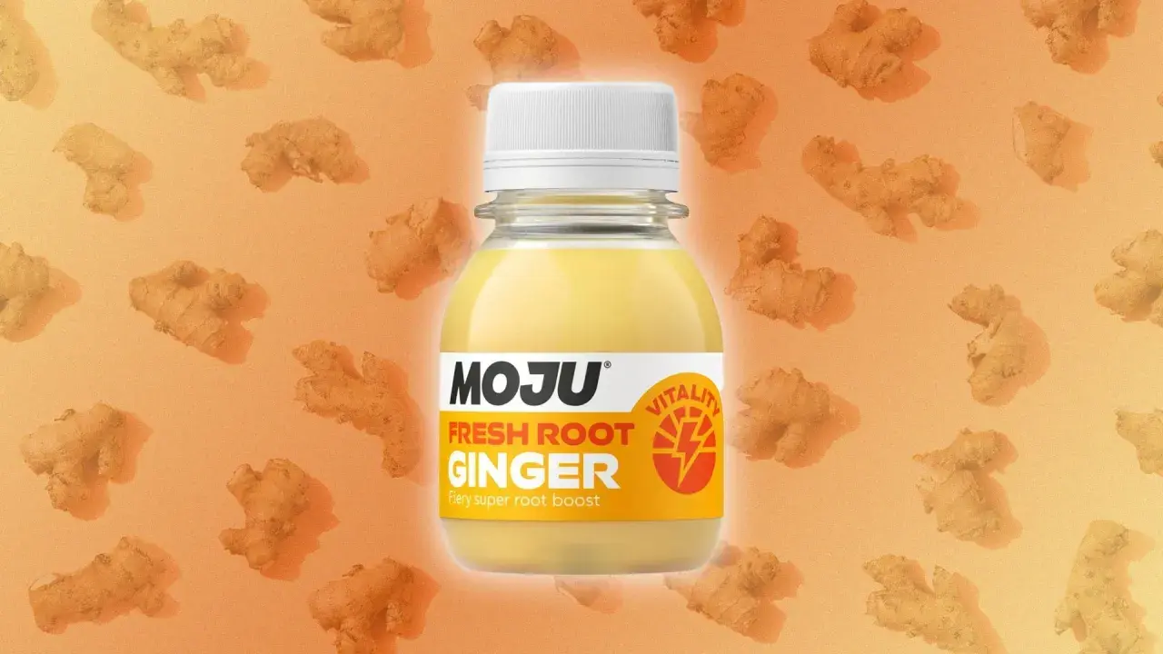 Botella de MOJU Fresh Root Ginger, destacando sus ginger shot beneficios. Fondo naranja con trozos de jengibre.