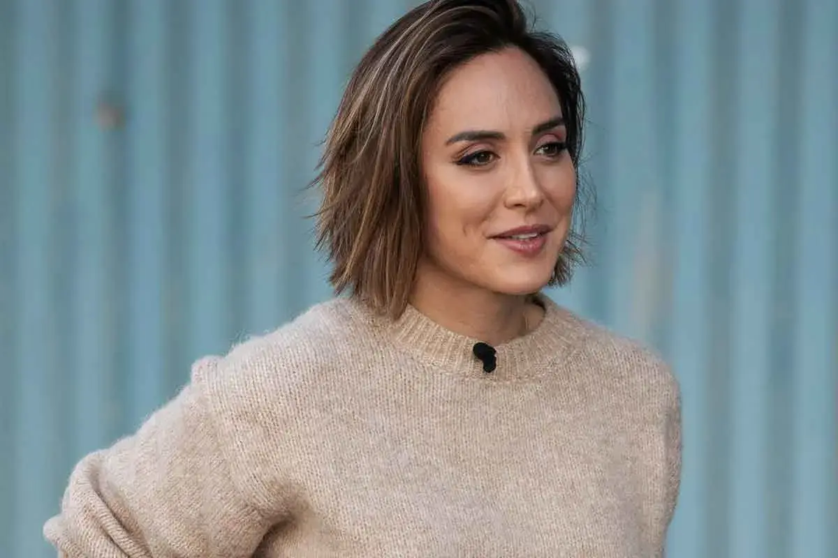 Mujer con un moderno corte de pelo bob, luciendo un suéter beige y una sonrisa amable.