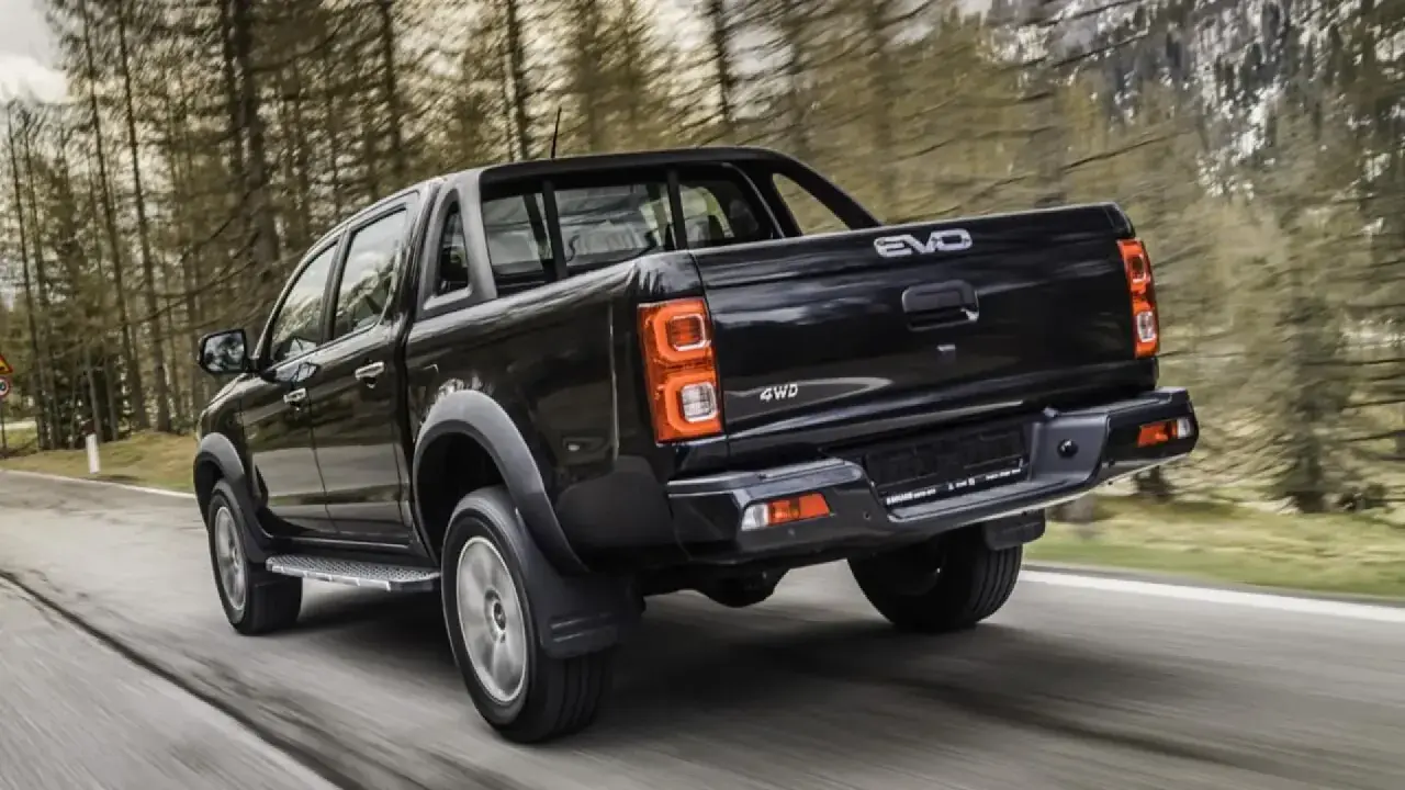 Camioneta negra 4WD en carretera boscosa. Buscando evo cross 4 opiniones para tu próxima aventura.