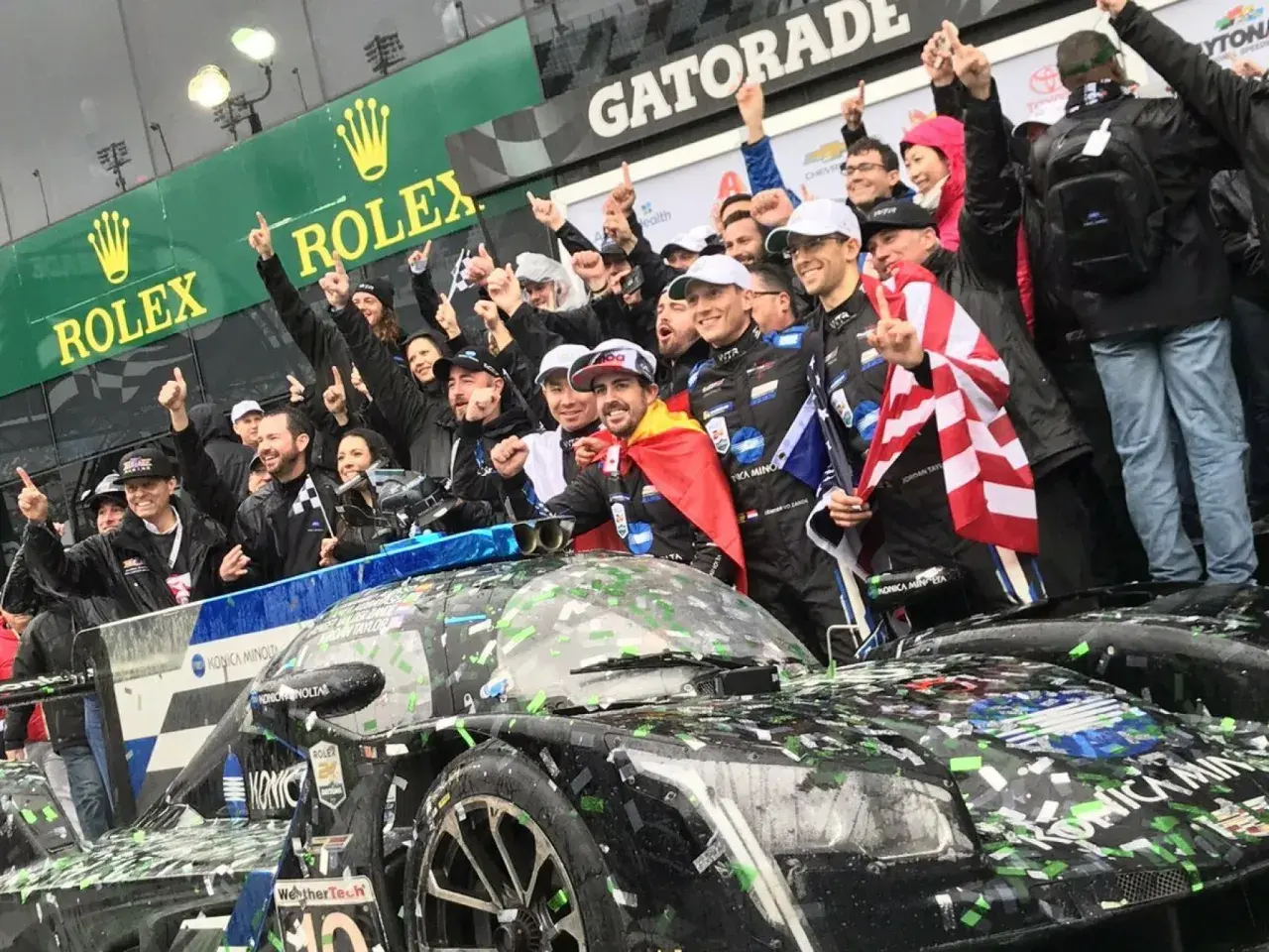 Fernando Alonso celebra la victoria en Daytona con su equipo, cubiertos de confeti y con banderas.