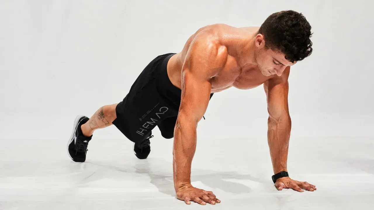 Hombre haciendo flexiones en posición de plancha, listo para un entrenamiento de hiit en casa.