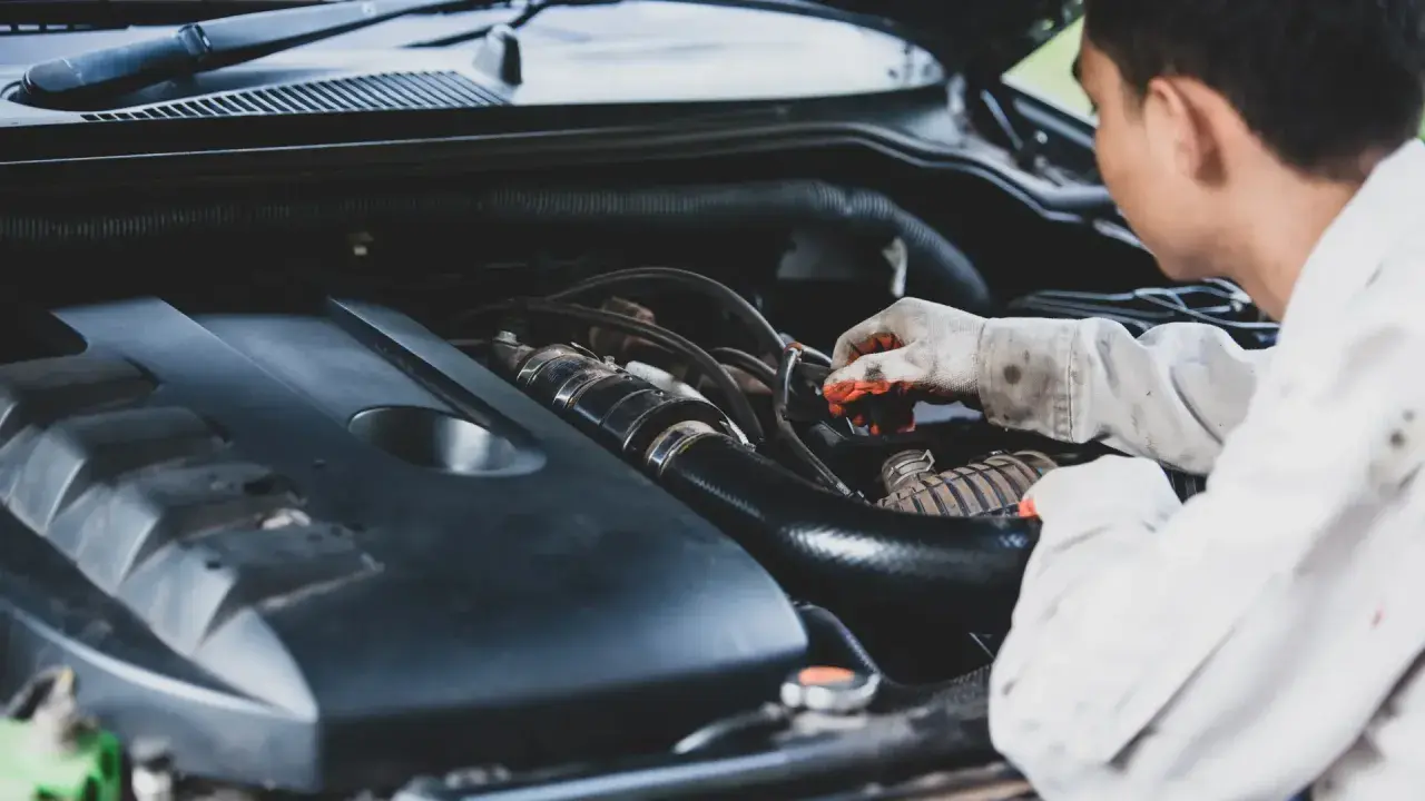 Mecánico revisa motor, buscando remedios caseros para quitar la carbonilla del coche.