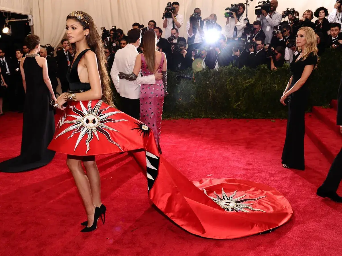 Zendaya deslumbrante en la Met Gala con un vestido rojo solar y una larga cola.