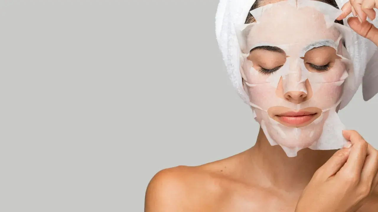 Mujer aplicándose mascarillas hidratantes pelo, con toalla en la cabeza.