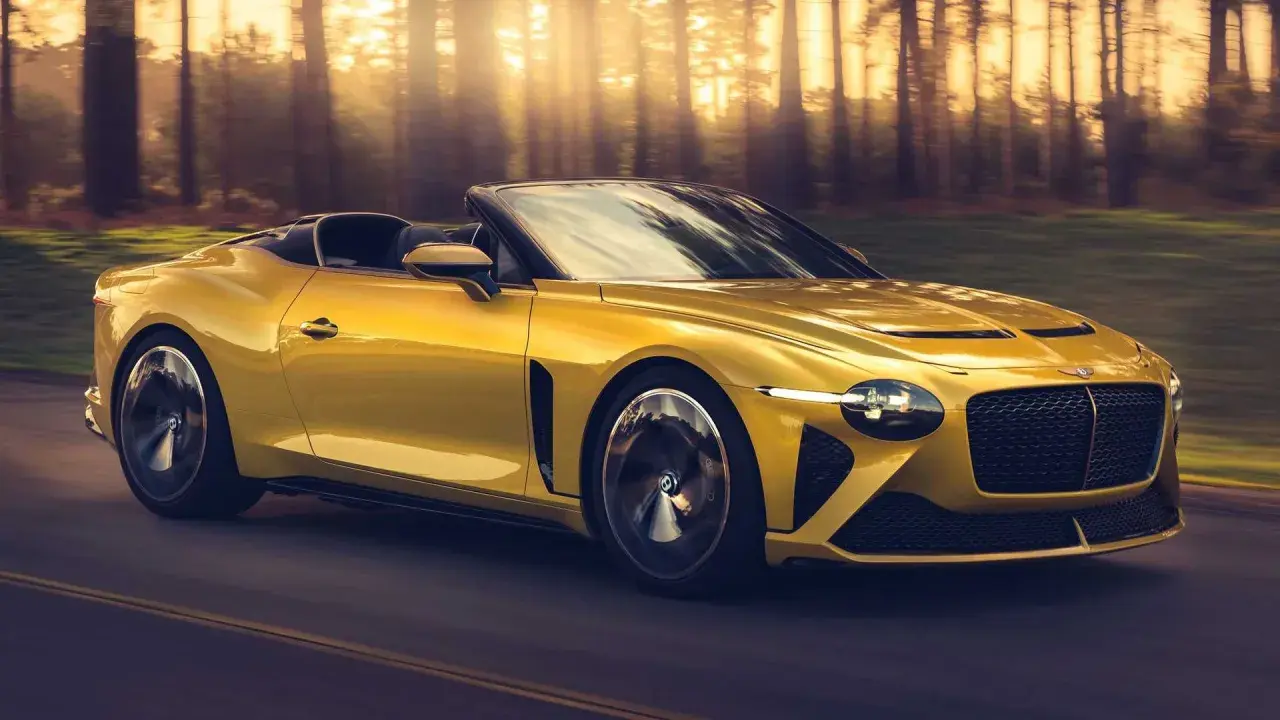 Un Bentley Mulliner Bacalar amarillo brillante recorre un camino boscoso al atardecer, con los rayos del sol filtrándose entre los árboles.