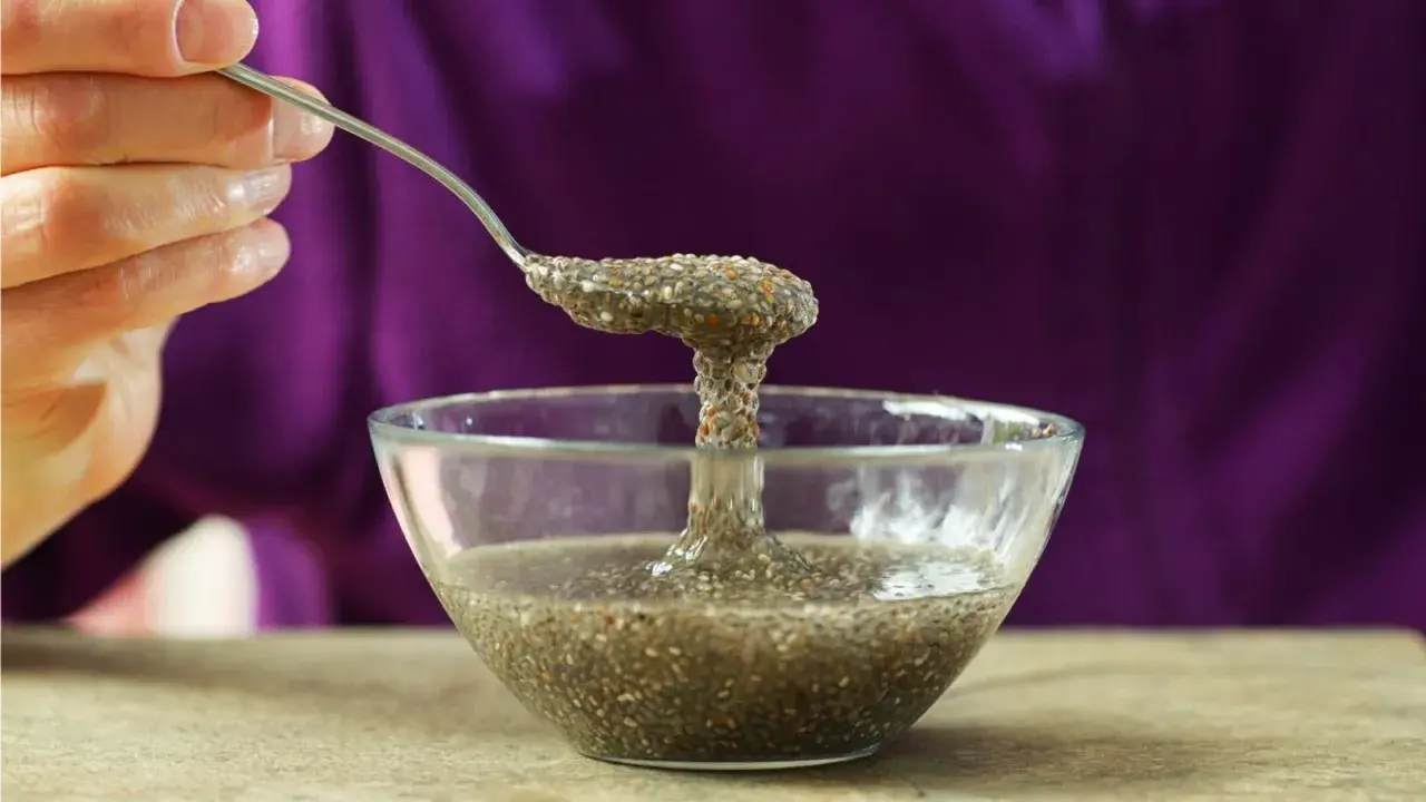 Cuchara levanta una porción gelatinosa de agua de chía de un cuenco de vidrio.
