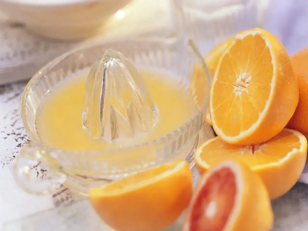 Exprimiendo naranjas frescas en un exprimidor de vidrio. El zumo de naranja natural recién hecho, listo para disfrutar.