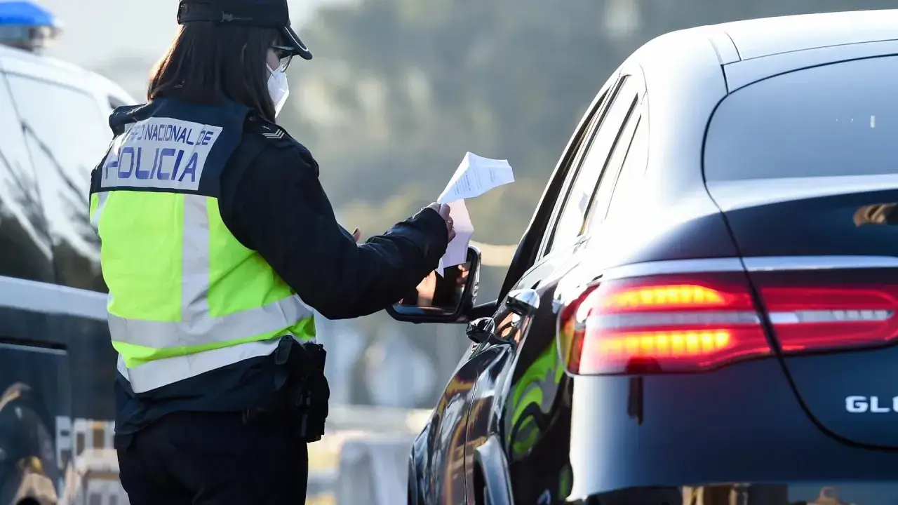Agente de policía revisa documentos, sospechando de un carnet de conducir falso.