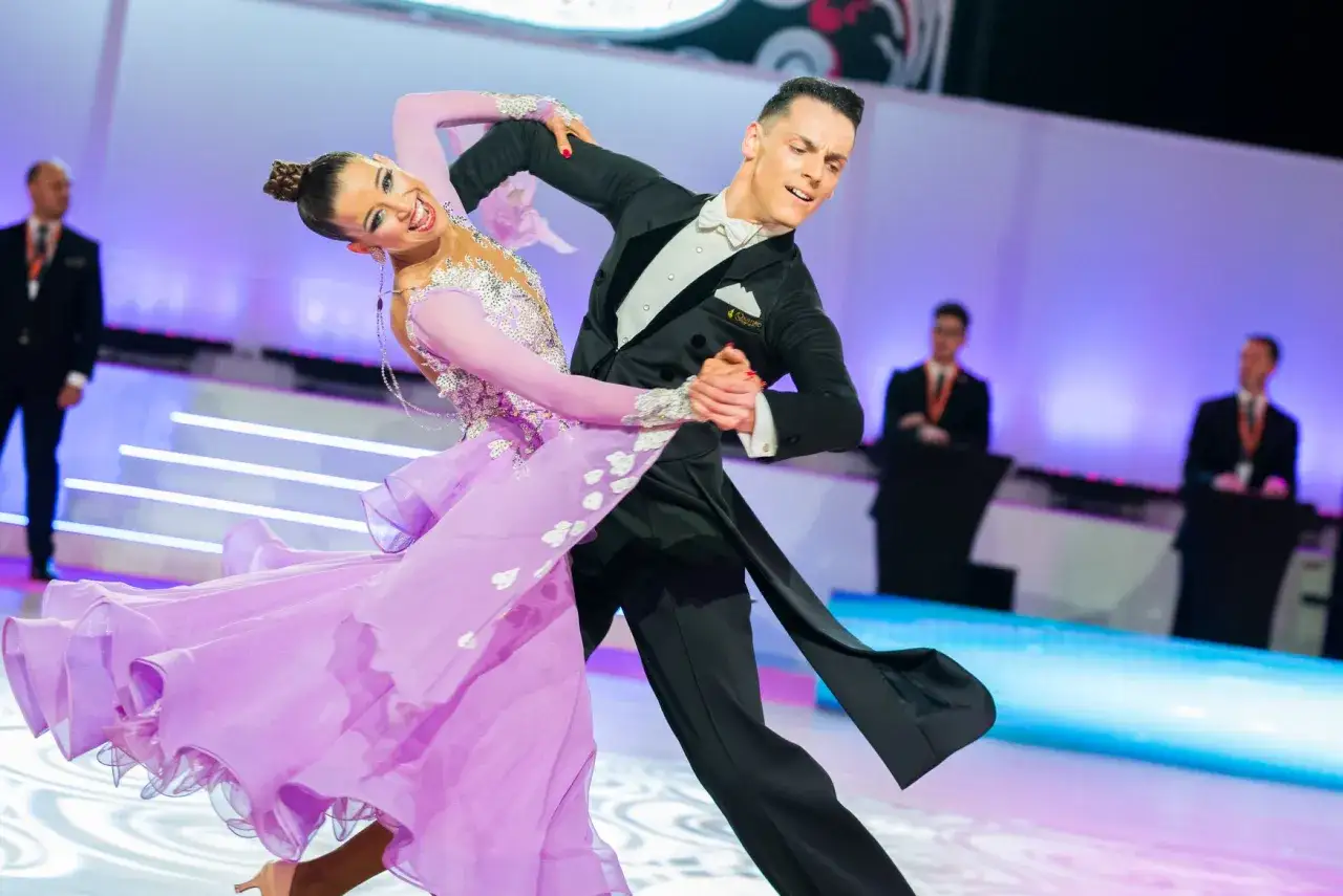 Pareja de baile de sal&oacute;n en competici&oacute;n, ella con vestido lila, &eacute;l con frac. Demuestran que el baile es un deporte.