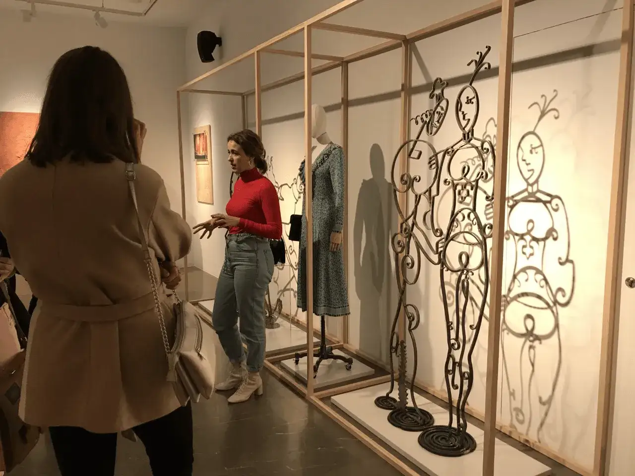 Una gu&iacute;a explica la historia de Loewe, de donde es la marca, frente a esculturas met&aacute;licas y maniqu&iacute;es en una exposici&oacute;n.