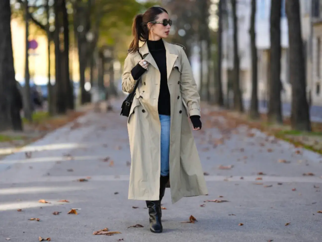 Mujer pasea con un elegante trench beige, su&eacute;ter negro y jeans, luciendo lo que se lleva este oto&ntilde;o.