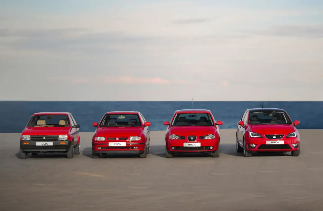 Cuatro generaciones de seat ibiza modelos, alineados frente al mar, mostrando la evolución del diseño automotriz.