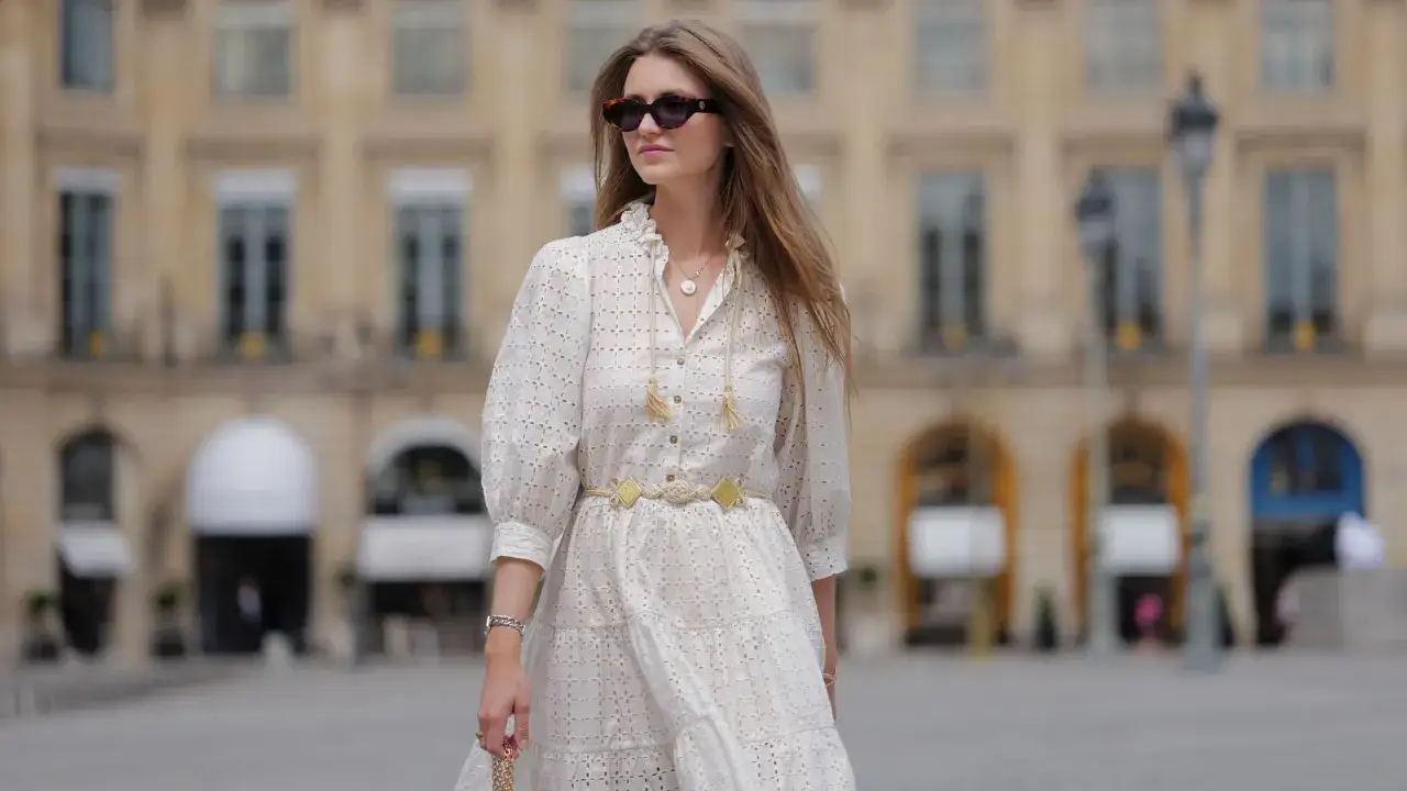 Estilo Jacqueline de Ribes: mujer con vestido blanco calado, cinturón de cuerda y gafas de sol, paseando por París.
