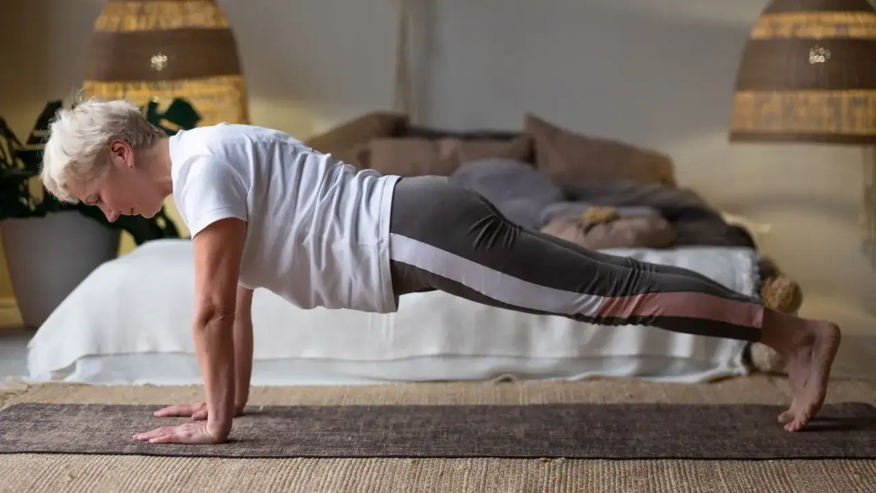 Mujer de 50 a&ntilde;os en posici&oacute;n de plancha, un ejercicio clave para perder grasa abdominal y tonificar.